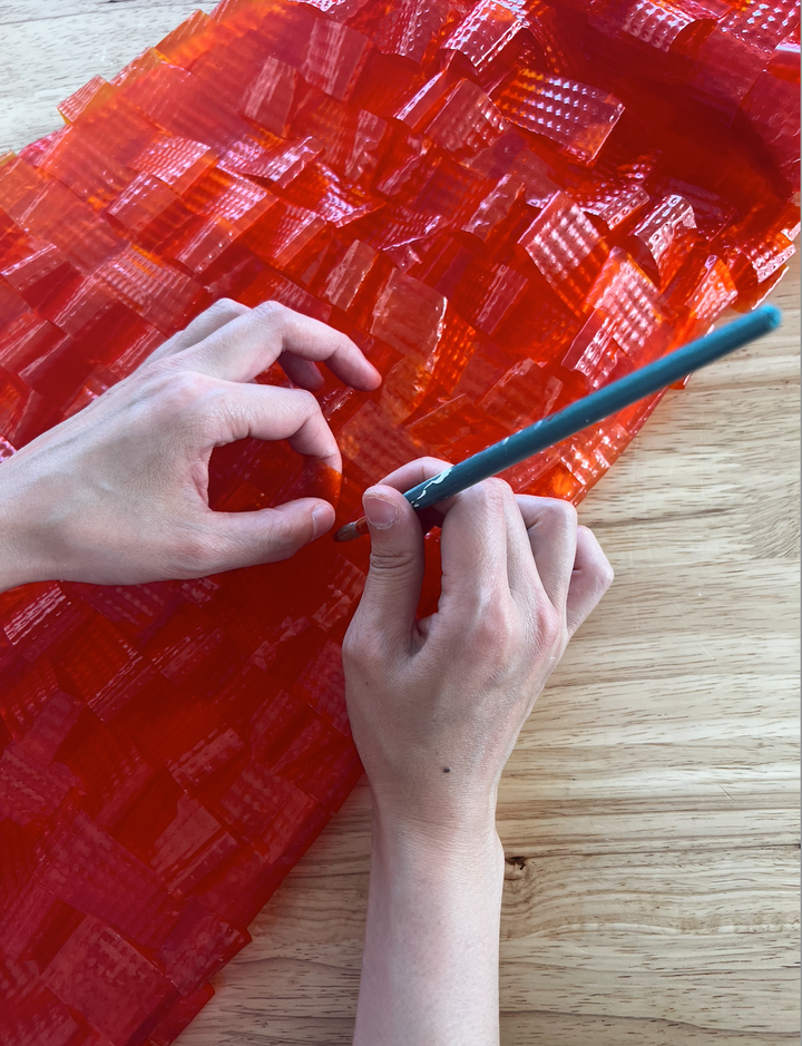Two hands working on red orange bioplastic sheets